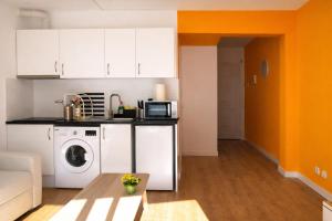 a kitchen with white cabinets and a washer and dryer at Beachfront apartment with sea views in Cunit