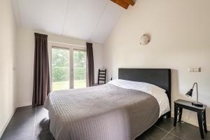 a white bedroom with a bed and a window at De Gemoedelijkheid in Nuenen