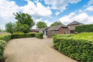 a house with a hedge in front of a driveway at De Gemoedelijkheid in Nuenen