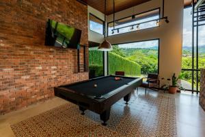 a pool table in a room with a brick wall at Villa Bosque CR in Turrialba