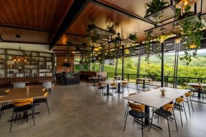 a restaurant with tables and chairs and large windows at Villa Bosque CR in Turrialba