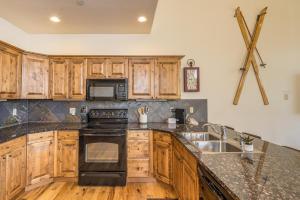 a kitchen with wooden cabinets and a black stove top oven at Alpenglow Condo 36A in Big Sky