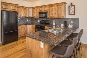 a kitchen with a black refrigerator and wooden cabinets at Alpenglow Condo 36A in Big Sky