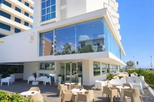 a restaurant with tables and chairs in front of a building at Hotel Regina Fronte Mare in Rimini