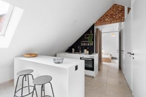 a kitchen with white counters and stools in a room at The barn - Waasmunster in Waasmunster