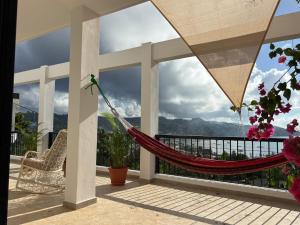 a hammock on a balcony with a view of the mountains at Villa Aurora Samaná in Santa Bárbara de Samaná