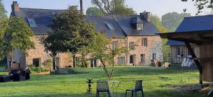 a large brick house with two chairs and a table in the yard at La suite de L'Eau qui dort in Pleslin-Trigavou