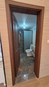 a bathroom with a toilet and a glass doorway at Taj Wadi Rum camp in Wadi Rum