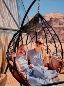 two women are sitting in a swing at Taj Wadi Rum camp in Wadi Rum