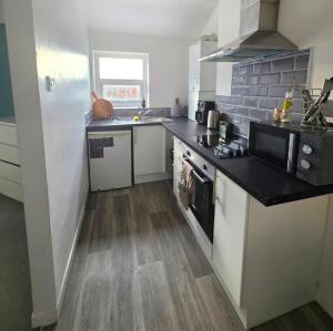 a kitchen with white cabinets and a black counter top at Sleepy Snug in Swansea