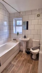 a bathroom with a tub and a sink and a toilet at Sleepy Snug in Swansea