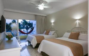 a hotel room with two beds and a window at Hotel Las Americas Casa de Playa in Cartagena de Indias