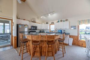 a kitchen with a center island with bar stools at Ocean Wynns - Nags Head MP 13, 20 Yards to the Beach, Ocean Views, Close to Attractions in Nags Head