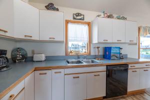 a kitchen with white cabinets and a sink and a window at Ocean Wynns - Nags Head MP 13, 20 Yards to the Beach, Ocean Views, Close to Attractions in Nags Head
