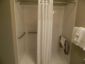 La salle de bains est pourvue d'une douche avec un rideau de douche blanc. dans l'établissement Brookstone Lodge & Suites, à Algona