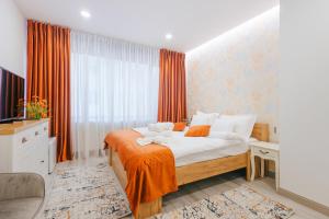 a bedroom with a large bed with orange curtains at Damone Residence in Gura Humorului
