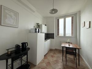 a kitchen with a table and a white refrigerator at L'appartement Dunois in Châteaudun