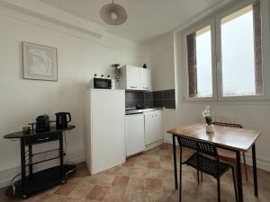 a kitchen with a table and a white refrigerator at L'appartement Dunois in Châteaudun +16 photos