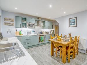 a kitchen with blue cabinets and a wooden table with chairs at Carrie's Gate in Coniston +17 photos