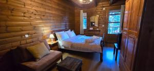 a bedroom with a bed and a couch in a log cabin at Panorama Elatis in Elati