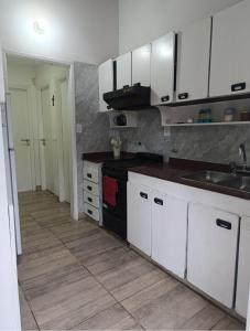 a kitchen with white cabinets and a sink at Nafaro in Villa Gesell