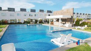 a swimming pool with two white chairs and a building at CASA CON ALBERCA Rodeada de NATURALEZA in Naranjo