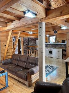 a living room with a leather couch in a log cabin at Lozanski ambar in Boljevac