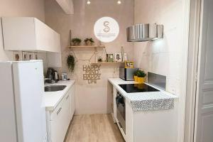 a small kitchen with white cabinets and a refrigerator at Coté Nature Arles Centre in Arles