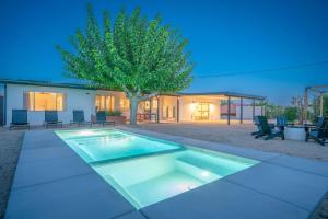 a swimming pool in front of a house with a tree at Joshua Tree Mid Mod - Pool - Spa - Sauna - Fire pit in Yucca Valley