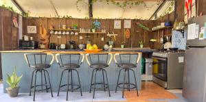 a kitchen with three bar stools at a counter at Rooms & Pool Macaws in Uvita