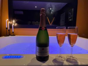 a bottle of champagne and two glasses on a tub at Cc love in Carbonne