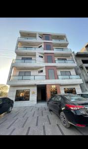 a tall building with two cars parked in front of it at Livora stays Cozy Luxury 1BHK in Multan