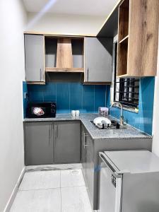 a kitchen with blue walls and a counter top at Livora stays Cozy Luxury 1BHK in Multan