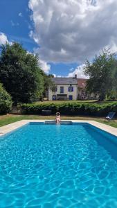 a person in a swimming pool with a house in the background at Les Marronniers Gîtes in Crozant
