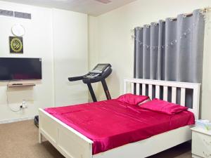 a bedroom with a bed with red sheets and a television at Qidfa apartment in Qidfi‘