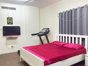 a bedroom with a bed with red sheets and a television at Qidfa apartment in Qidfi‘