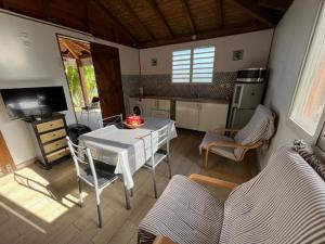 a living room with a table and a kitchen at Coin tranquille in Sainte-Anne