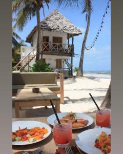 a table with plates of food on the beach at Mango Beach House in Jambiani