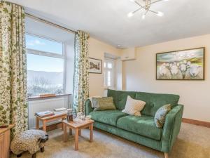 a living room with a green couch and a window at Carrie's Gate in Coniston