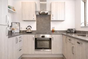 a kitchen with white cabinets and a stainless steel oven at Margate Penthouse Private Balconies Sea Glimpses Gated Parking Air-Con The Penthouse Margate in Margate +13 photos