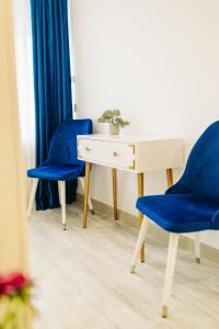 two blue chairs and a desk with a plant on it at Damone Residence in Gura Humorului +27 photos