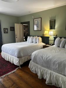 two beds in a hotel room with two bedsskirts at Garrison House Inn in Annapolis Royal