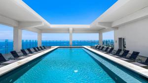 a swimming pool in a building with chairs at Stunning Beachfront Condo - Sea Views & Pools in Puerto Vallarta