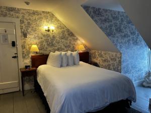 a bedroom with a white bed with blue wallpaper at Garrison House Inn in Annapolis Royal