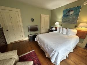 a bedroom with a large white bed and a tv at Garrison House Inn in Annapolis Royal