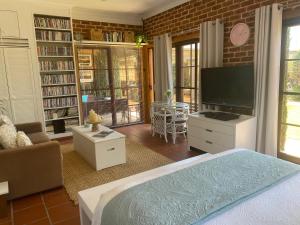 a living room with a bed and a flat screen tv at Ciara's Cottage CC'S in Illawong