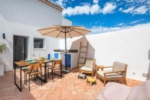 a patio with a table and chairs and an umbrella at Quinta do Ourives in Carvoeiro
