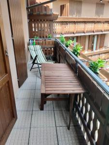 a balcony with a wooden bench and two chairs at Appartamento bambi abetone in Abetone