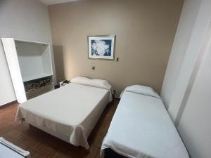 a room with two beds and a mirror at Hotel Jaú in Jaú