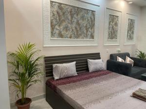 a bedroom with a bed and a couch and paintings at StayVerse74 in Noida